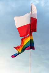 Polska oraz tęczowa flaga z barwami LGBT na tle niebieskiego nieba z białymi chmurami © Mikołaj Rychter