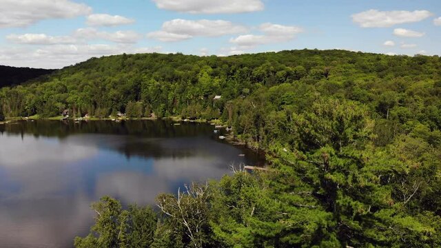 A descending shot over a forest and a lake in cottage country.