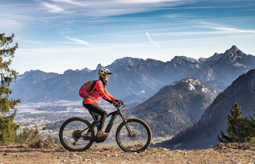 pretty senior woman riding her electric mountain bike in the mountains of East Allgaeu on warm...