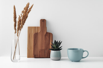 A mug, a potted houseplant, a clear vase and a wooden cutting board. Eco-friendly materials in the decor of the room, minimalism. Copy space, mock up.