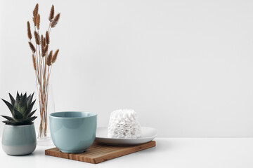 Blue mug and meringue cake on a white background. Eco-friendly and natural materials in decor and interior design, dessert. Copy space, mock up.