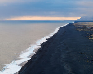 Waves crashing at black sand beach in South Iceland. Late evening light in winter.