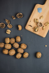 Walnuts on black, dark background, with opening tool on a wooden cutting board. Opening walnuts and taking them out of their shell