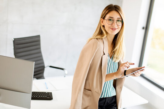 Young business woman holding digital tablet and standing in the modern office