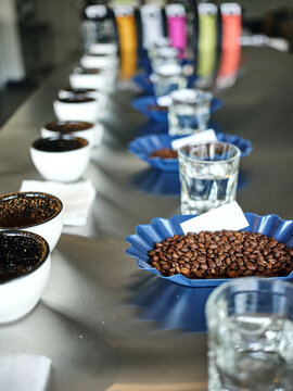 The best flavors. Close up shot of process of coffee cupping. Coffee is poured into tasting cups. Assortment of freshly roasted and ground coffee beans in containers. Selective focus. Vertical shot