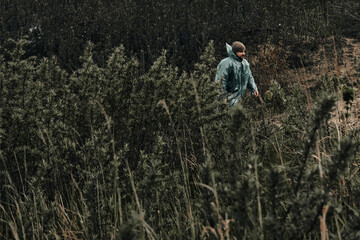Obraz premium A man in a green raincoat walks along a country road, cloudy, autumn.