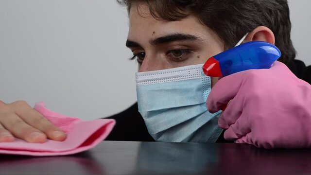 chico joven limpiando mesa con desinfectante