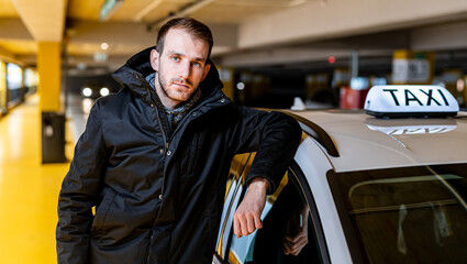 Taxi driver posing with his car at the underground parking