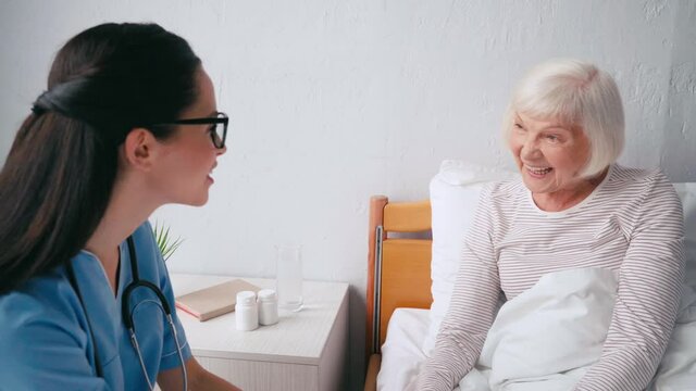 smiling senior woman talking to geriatrician in nursing home