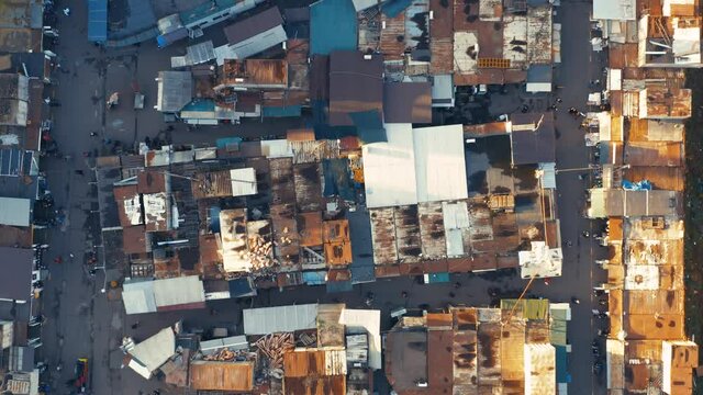 Aerial top down view of a bazaar in a slum with people between the rows
