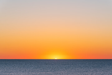 Orangefarbener Sonnenaufgang über dem Meer und dem Sandstrand
