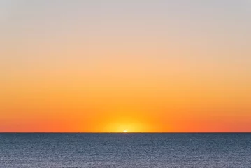 Fotobehang Oranje zonsopgang boven de oceaan en het zandstrand © Melissa