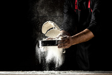 the chef sprinkles flour through a sieve, Powdery flour flying into air. chef hands with flour in a freeze motion of a cloud of flour midair