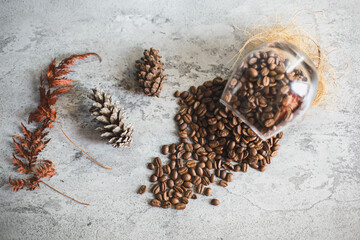 Flat lay of coffee beans with dried flowers on wooden board isolated by grey concrete wall, autumn concept