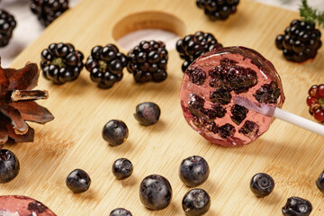 Homemade lollipops made from natural dehydrated bilberry and blackberries on a white wooden background. Healthy vegan vegetarian food with no sweets.