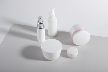 Set of white cosmetic bottles and jars with hard shadows. Home and beauty salon care concept