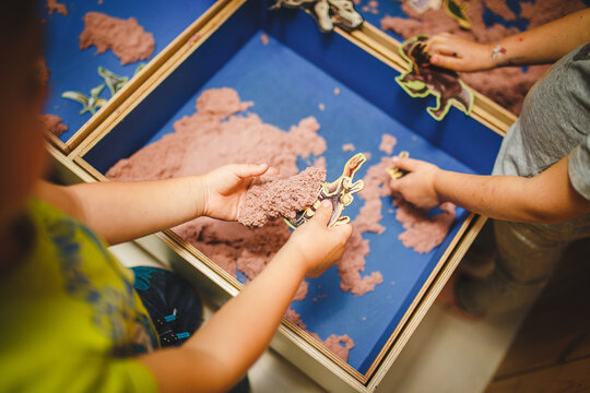 children moulds from plasticine on table, Child hands playing with colorful clay, day care close up, tactility activity with dinosaur figures
