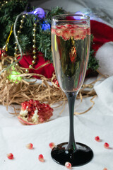 Close-up. Christmas background. Pomegranate in a glass of champagne. Vertical photography. In the background, a pomegranate fruit.
