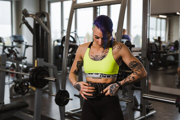 Fototapeta premium tattooed woman preparing for power lifting in gym