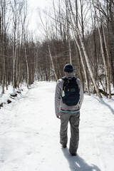 man casting shadow in snow on trail through winter forest close up