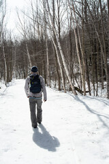 Fototapeta na wymiar hiker casting shadow on snow on trail through winter forest