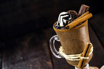bowl of hot chocolate with hot syrup, marshmallows, cocoa and sugar. Sweet and hot winter drink with black background