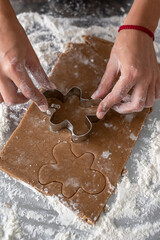 Woman cutting some gingerbread dough with a metal cookie cutter man