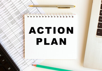 Notepad with text ACTION PLAN on a white background, near laptop, calculator.