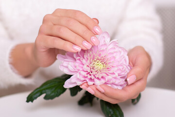 Obraz na płótnie Canvas Female hands with beautiful manicure nails, nude gel polish, holding peony flower