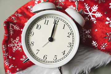 White alarm clock lying on the background of a new year red cap, new year