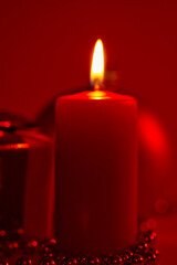 Burning candle and Christmas decoration red dark background, elegant low-key shot with festive mood
