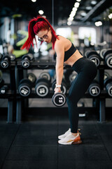 strong fitness woman training with heavy weights in fitness gym. Female athlete holding barbell during back workout