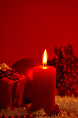 Obraz na płótnie Canvas Burning candle and Christmas decoration red dark background, elegant low-key shot with festive mood
