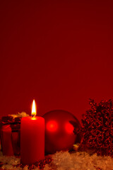 Burning candle and Christmas decoration red dark background, elegant low-key shot with festive mood