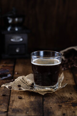 Black coffee in a glass with brown sugar crystals