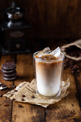 Iced coffee in a tall glass on wooden background