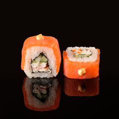 Two sushi rolls dragon syake on a black background with reflection. Sushi menu, japanese kitchen.