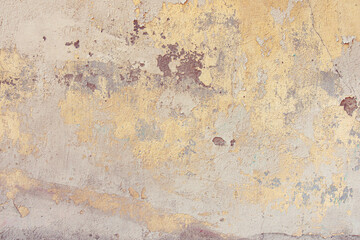Old cracked weathered painted wall background texture. Yellow dirty peeled plaster wall with falling off flakes of paint