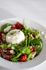 Salad with Italian burrata cheese, arugula, cherry tomatoes, parmesan and raspberry