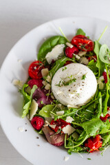 Salad with Italian burrata cheese, arugula, cherry tomatoes, parmesan and raspberry