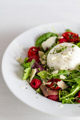 Salad with Italian burrata cheese, arugula, cherry tomatoes, parmesan and raspberry
