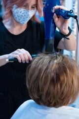 Hairdresser combing and drying a lady