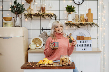 Caucasian blonde woman congratulates with Merry Christmas. At home, in kitchen