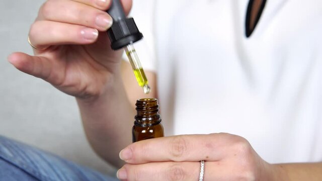 Close-up of females hand holding bottle with cbd oil drops. Concepts of alternative medicine and herbs