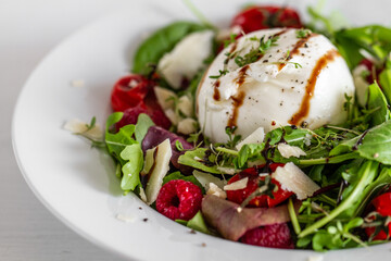 Salad with Italian burrata cheese, arugula, cherry tomatoes, parmesan and raspberry with balsamic glaze