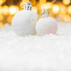 Decorative Christmas balls laying in a snow with yellow lights bokeh on the background. Greeting...