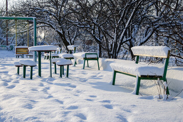 Snow-covered playground with swings and benches