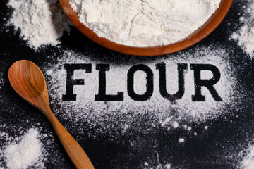 Cup with white flour. Wooden spoon. A few handfuls of flour. In the center of the inscription.