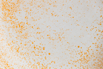 Fototapeta na wymiar White ceramic surface stained with orange color splatter drops forms an abstract landscape with rusty texture as a background.