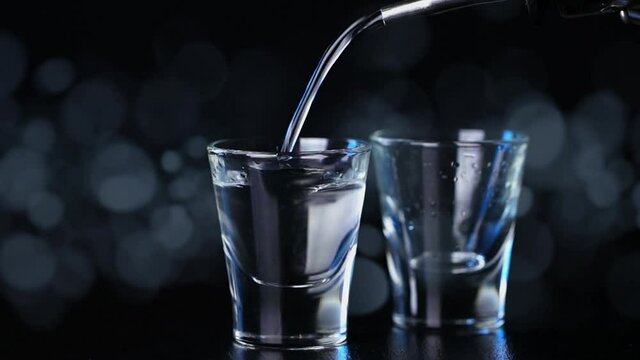 cinemagraph, vodka is poured into a glass on black background